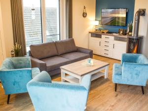 a living room with a couch and chairs and a table at Auszeit im Sielhuus - Familienfreundliche Ferienwohnung mit Dachterrasse und Sauna in Fedderwardersiel