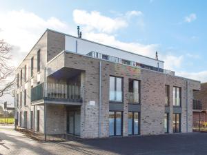 a brick building with a balcony on a street at Auszeit im Sielhuus - Familienfreundliche Ferienwohnung mit Dachterrasse und Sauna in Fedderwardersiel