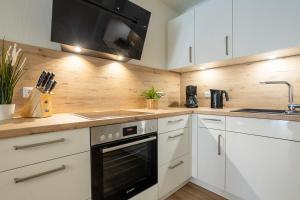 a kitchen with white cabinets and a black oven at Dorumer Seestern - Ferienwohnung mit Terrasse und Sauna in Dorum