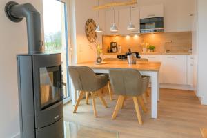 a kitchen with a table and chairs and a stove at Deichbude Tossens - Modernes Ferienhaus für 4 Personen in Butjadingen OT Tossens