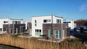 a row of houses in a field of tall grass at Deichbude Tossens - Modernes Ferienhaus für 4 Personen in Butjadingen OT Tossens