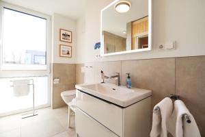 フェーマルンにあるBeltBlick 11 – Ferienwohnung mit unverbautem Meerblick & Dachterrasse!の洗面台と鏡のあるバスルーム +17枚の写真