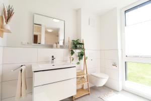 une salle de bain blanche avec un lavabo et des toilettes dans l'établissement BeltBlick 14- Küstenleuchten - Moderne Ferienwohnung direkt am Strand mit Sauna und Garten!, à Fehmarn 19 autres photos