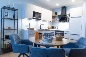 a kitchen with a table and blue chairs in a room at Dorumer Sielhuus 20 mit Sauna und Balkon in Dorum