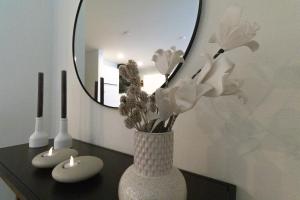 a vase with flowers on a table in front of a mirror at Dorumer Sielhuus 20 mit Sauna und Balkon in Dorum