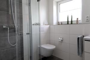 a bathroom with a toilet and a glass shower at FeWo Seebrise mit Sauna und Balkon in Dorum +17 photos