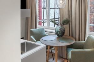a room with a table with chairs and a vase on it at Distillery Apartments in Lüneburg