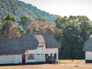a white house with a car parked in front of it at Mount Sheba Rainforest & Resort in Pilgrim's Rest