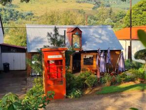 Eine alte rote Telefonzelle vor einem Haus in der Unterkunft Mount Sheba Rainforest & Resort Self Catering Cottages in Pilgrimʼs Rest