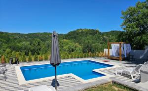 a swimming pool with an umbrella and a table and chairs at Vila Monti  +4 photos