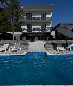 a hotel with a swimming pool with chairs and a building at Vila Monti 