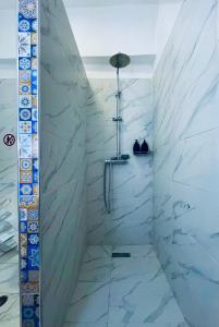 a bathroom with a shower with white marble walls at Tirana Center Apartments in Tirana