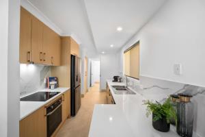 a kitchen with white counter tops and wooden cabinets at Coastal Central 3BR - Spa, Surfers Paradise, AC in Gold Coast