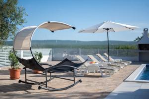 un gruppo di sedie e ombrelloni accanto a una piscina di Holiday Home Lantina with pool a Pridraga
