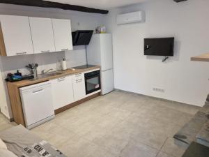 a small kitchen with white cabinets and a tv at Maison Samuela in Grillasca
