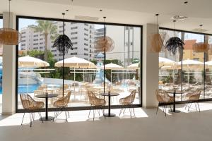 a restaurant with tables and chairs and a pool at Hotel RH Arena - Todo Incluido in Gandía