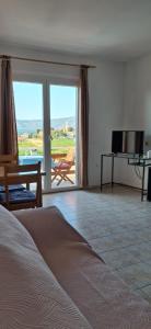 a bedroom with a bed and a television and a balcony at House Baglija in Lumbarda