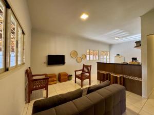 a living room with a couch and a tv at Casa das Orquídeas Delfinopolis MG in Delfinópolis