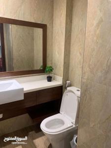 a bathroom with a toilet and a sink and a mirror at شقة فندقية بمنتجع ميلينيوم in Salalah
