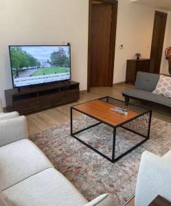 a living room with a television and a coffee table at شقة فندقية بمنتجع ميلينيوم in Salalah