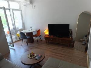 a living room with a flat screen tv and a table at Sofi in Sutomore