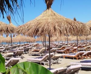 a bunch of lounge chairs and umbrellas on a beach at Super Leisure Vila-Plazhi San Pietro, Gjiri i Lalezit in Lalzit Bay