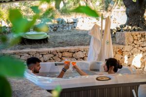 a man and woman in a hot tub with drinks at Come una volta - Il Trullo in Alberobello