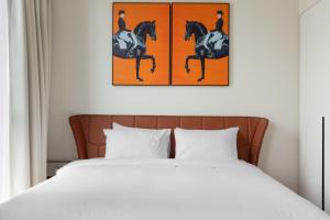 a bedroom with a bed and two paintings of horses at Sahab - Hermes Leather Home in Sharjah