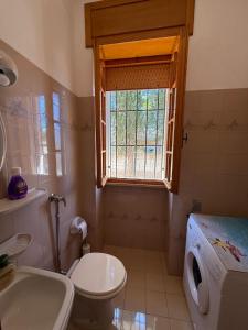 a bathroom with a toilet and a sink and a window at Villa Rosetta, Gallipoli tra mare e natura in Pizzo