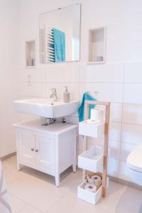 Un baño blanco con lavabo y espejo. en Inselblume 47 - Luxus Ferienwohnung in Burg, mit Dachterrasse, en Burg auf Fehmarn