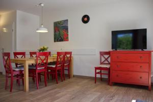 a dining room with a table and red chairs and a tv at Inselblume 28 - Ferienhaus mit Garten in Burg auf Fehmarn in Burg auf Fehmarn