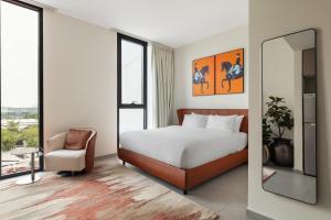 a bedroom with a bed and a chair and a mirror at Sahab - Hermes Leather Home in Sharjah +23 photos