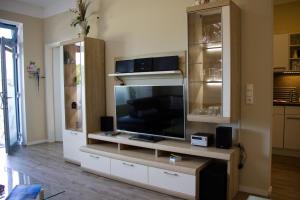 a living room with a entertainment center with a flat screen tv at Inselblume 49 - Ferienwohnung im Erdgeschoss der Strandburg in Burgtiefe auf Fehmarn 