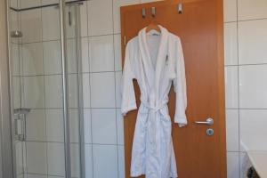 a robe hanging on a door in a bathroom at Inselblume 55 - Ferienwohnung in der Strandburg mit Hund in Burgtiefe auf Fehmarn  +15 photos