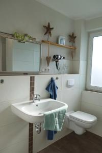 a white bathroom with a sink and a toilet at Inselblume 22 - Ferienhaus mit Garten und Hund in Landkirchen in Landkirchen
