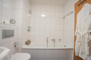 a white bathroom with a tub and a toilet at Inselblume 56 - Ferienwohnung am Südstrand mit Meerblick in Burgtiefe auf Fehmarn  +12 photos