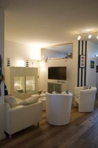 un salon avec des meubles blancs et une télévision à écran plat dans l'établissement Inselblume 24 - Exklusive Ferienwohnung in der Strandburg, à Burgtiefe auf Fehmarn  29 autres photos