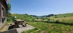 a wooden picnic table sitting on the side of a house at Chalet à Besse 10 personnes in Besse-et-Saint-Anastaise