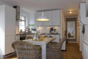 a kitchen with a table and wicker chairs at Inselblume 36 - Schöne Ferienwohnung in Neue Tiefe in Neue Tiefe Fehmarn +25 photos