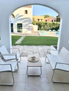 a patio with chairs and a table and a pool at Apartamento costa Menorca in Cala en Bosc +6 photos