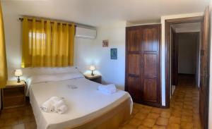 a bedroom with a white bed and a yellow curtain at Sardegna Beach Cala Reale in Santa Marinella