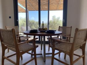 a dining room table with chairs and a table with a bowl of fruit at Spitaki Among Olives in Tsoukalades