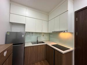 a kitchen with white cabinets and a black refrigerator at An Lạc 402MD in Hanoi