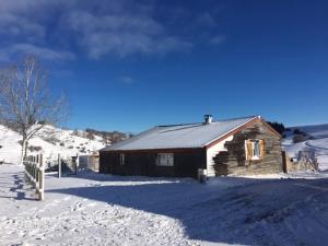 a wooden cabin in the snow with a fence at Chalet à Besse 10 personnes in Besse-et-Saint-Anastaise