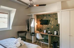 a bedroom with a bed and a desk and a tv at Hotel Restaurant La Musardiere in Giverny
