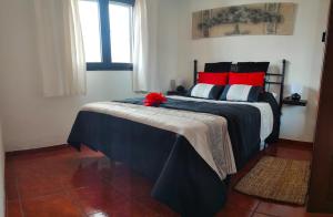 Un dormitorio con una cama con una flor roja. en Casita Oyala, en San Bartolomé