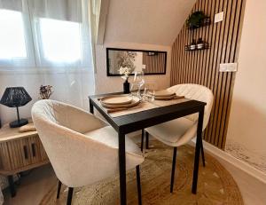 a dining room table with white chairs and a black table at Le Ptit Jumoku in Caen