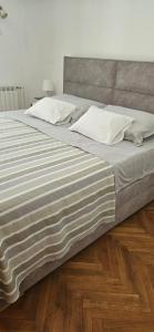a large bed with white pillows on a wooden floor at Cozy house Luana in Lopud Island
