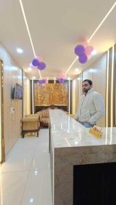a man sitting at a kitchen counter with purple balloons at Family Hotel -1 Min Walk in Nizamuddin Railway Station in New Delhi