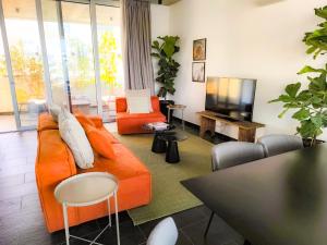 a living room with an orange couch and a television at Bridge House 301-3BR Penthouse in Limassol
